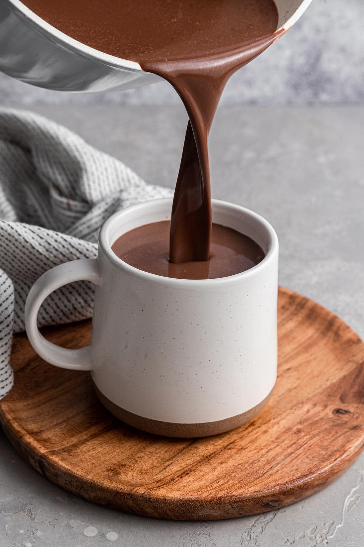 thick italian hot chocolate being poured into a white mug.