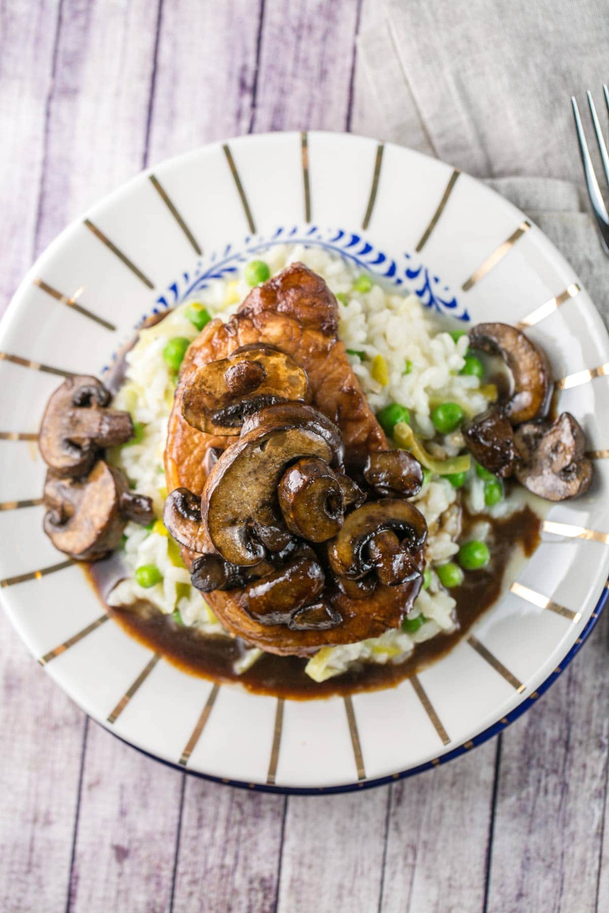 overhead view of a pork chop covered with mushrooms and sauce