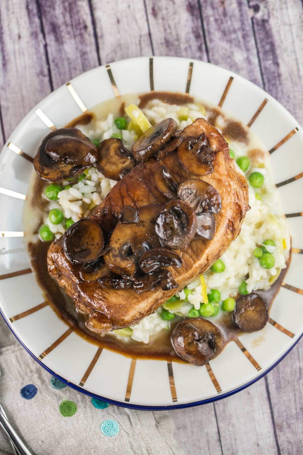 seared pork chop placed and risotto on a decorative gold plate