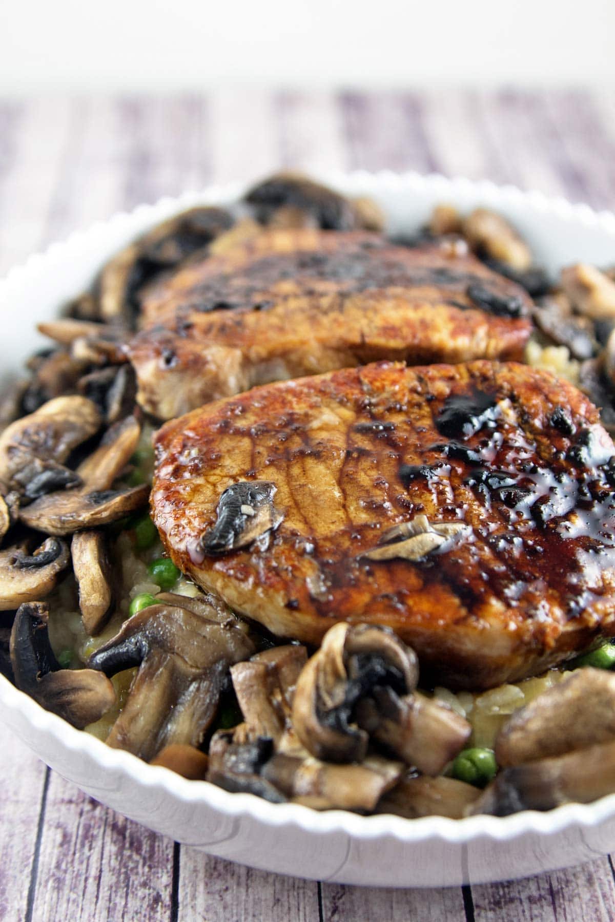 two perfectly seared pork chops surrounded by sliced mushrooms