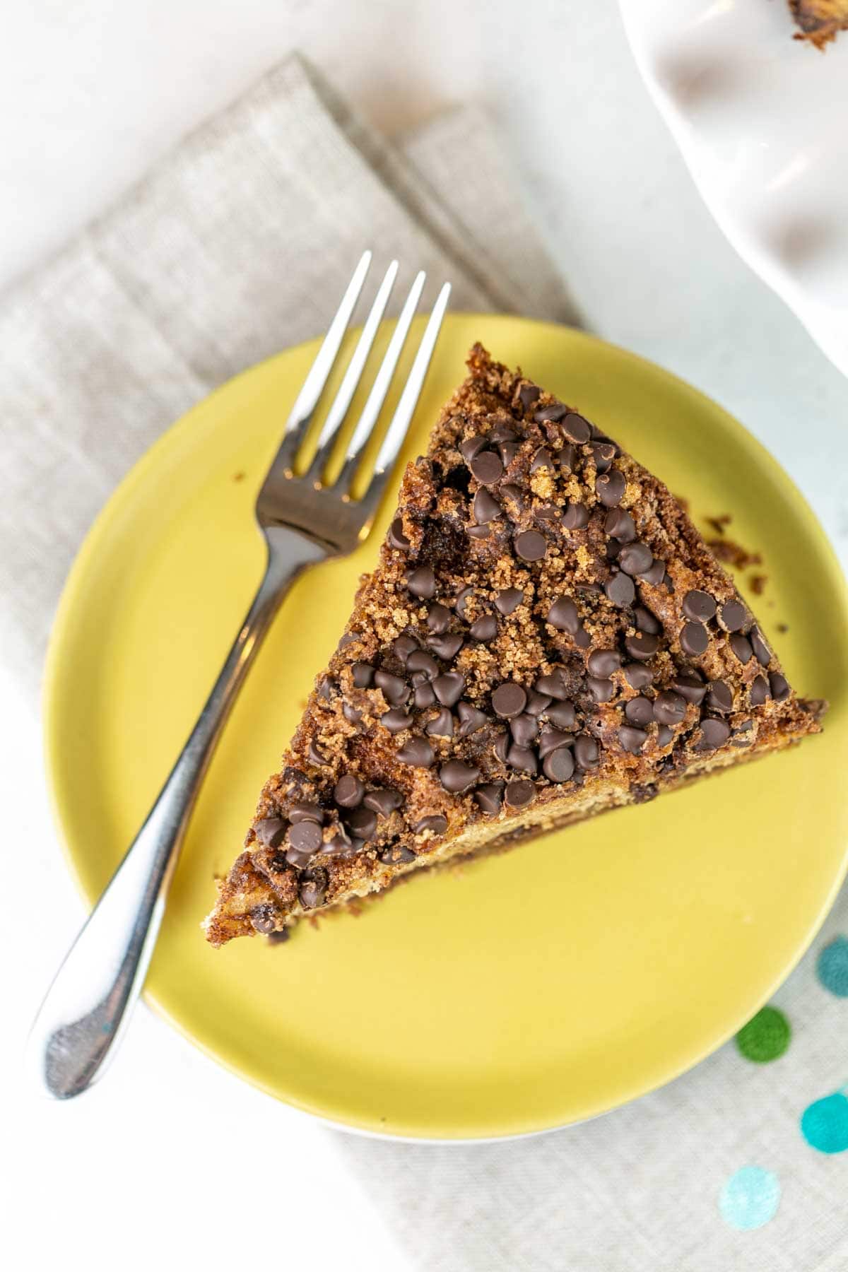 slice of cake on a yellow plate highlighting the chocolate chip streusel topping