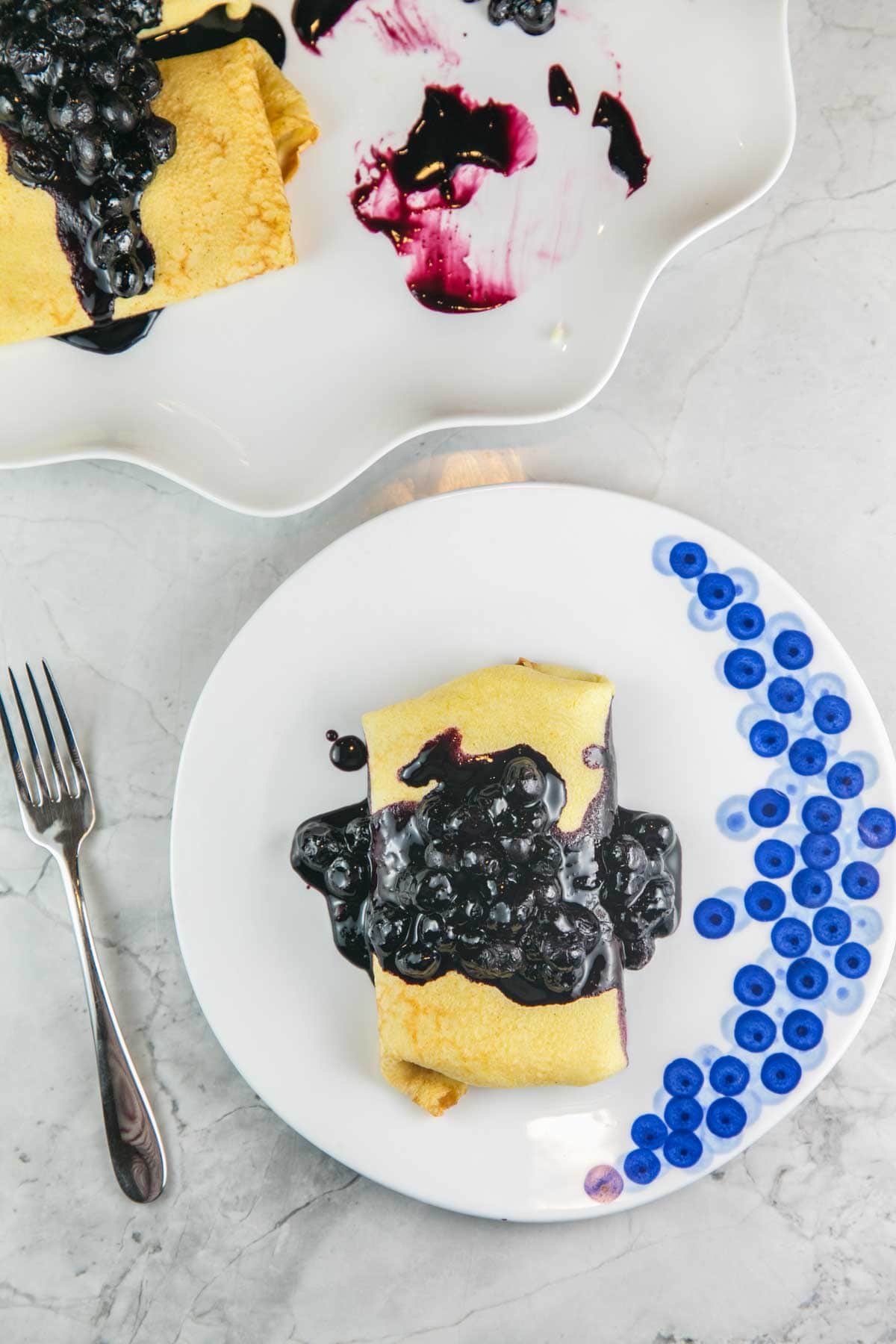 overhead view of a blintz on a blueberry painted plate