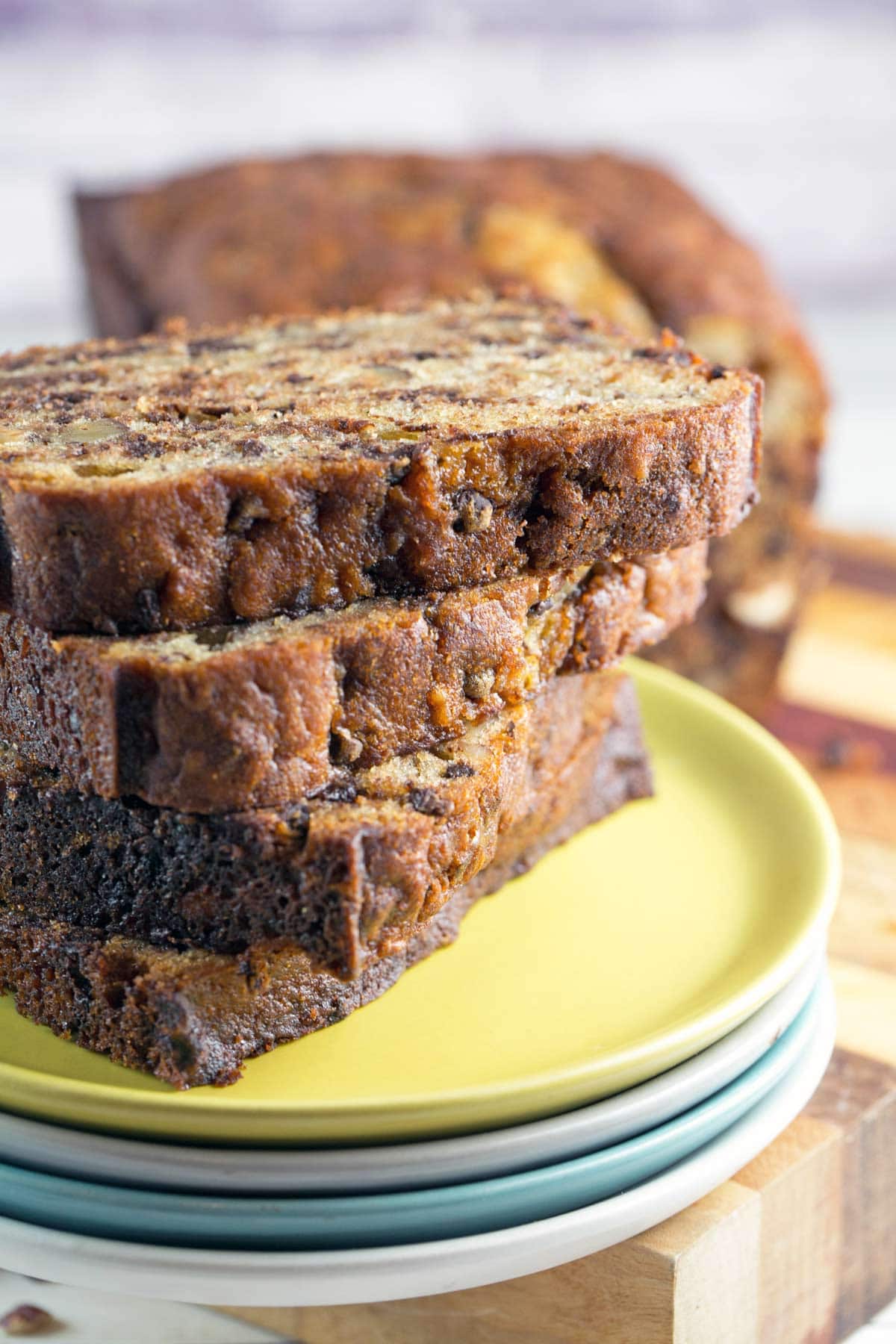 four slices of chocolate chip banana bread stacked on a pile of dessert plates