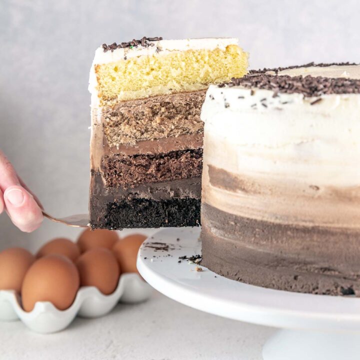 slice of ombre chocolate cake with ombre frosting being cut from a whole cake