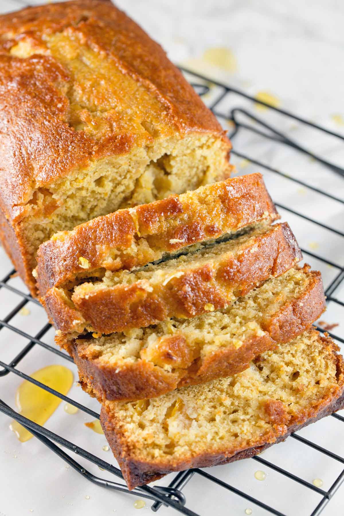 sliced quick bread covered in simple syrup glaze on a wire cooling rack