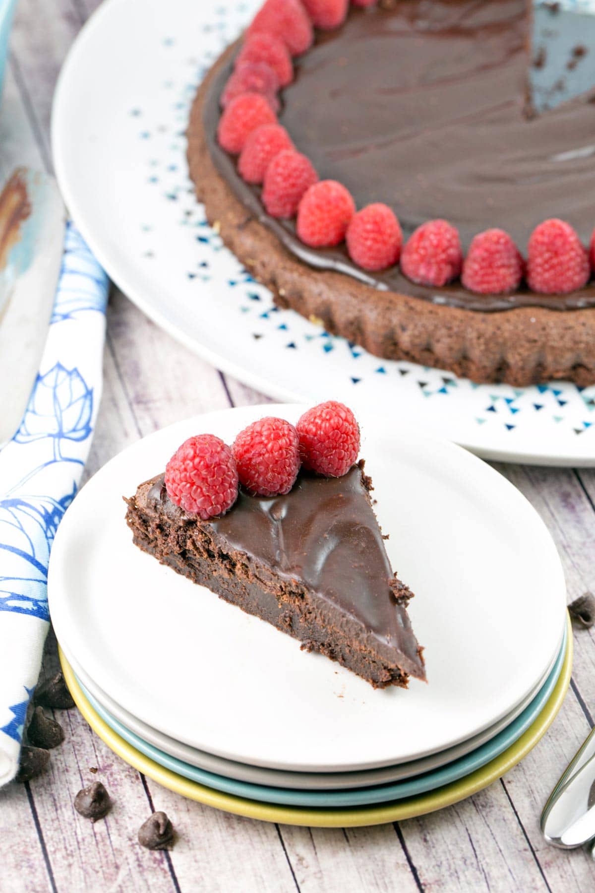 a large cut slice of flourless chocolate cake on a stack of dessert plates