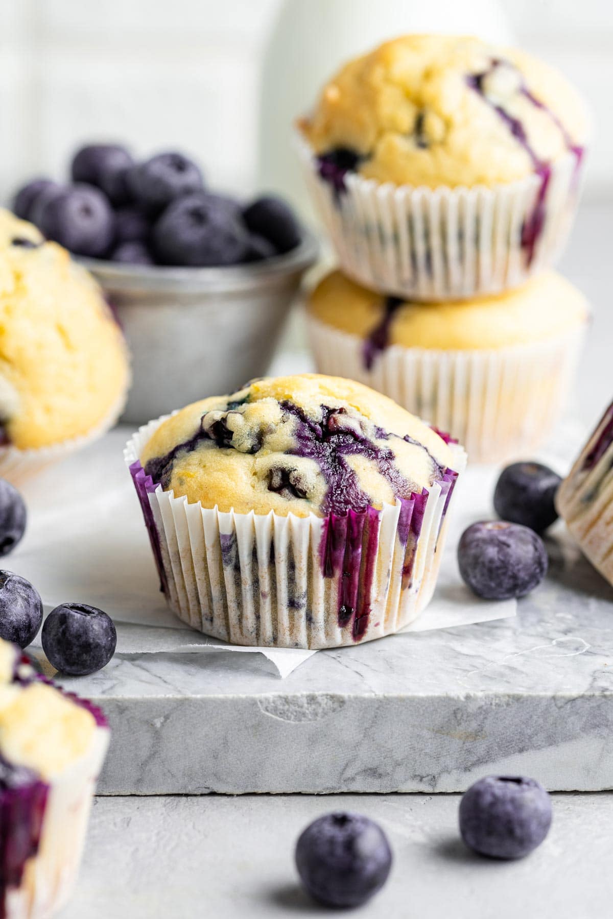 muffins in white paper liners surrounded by blueberries