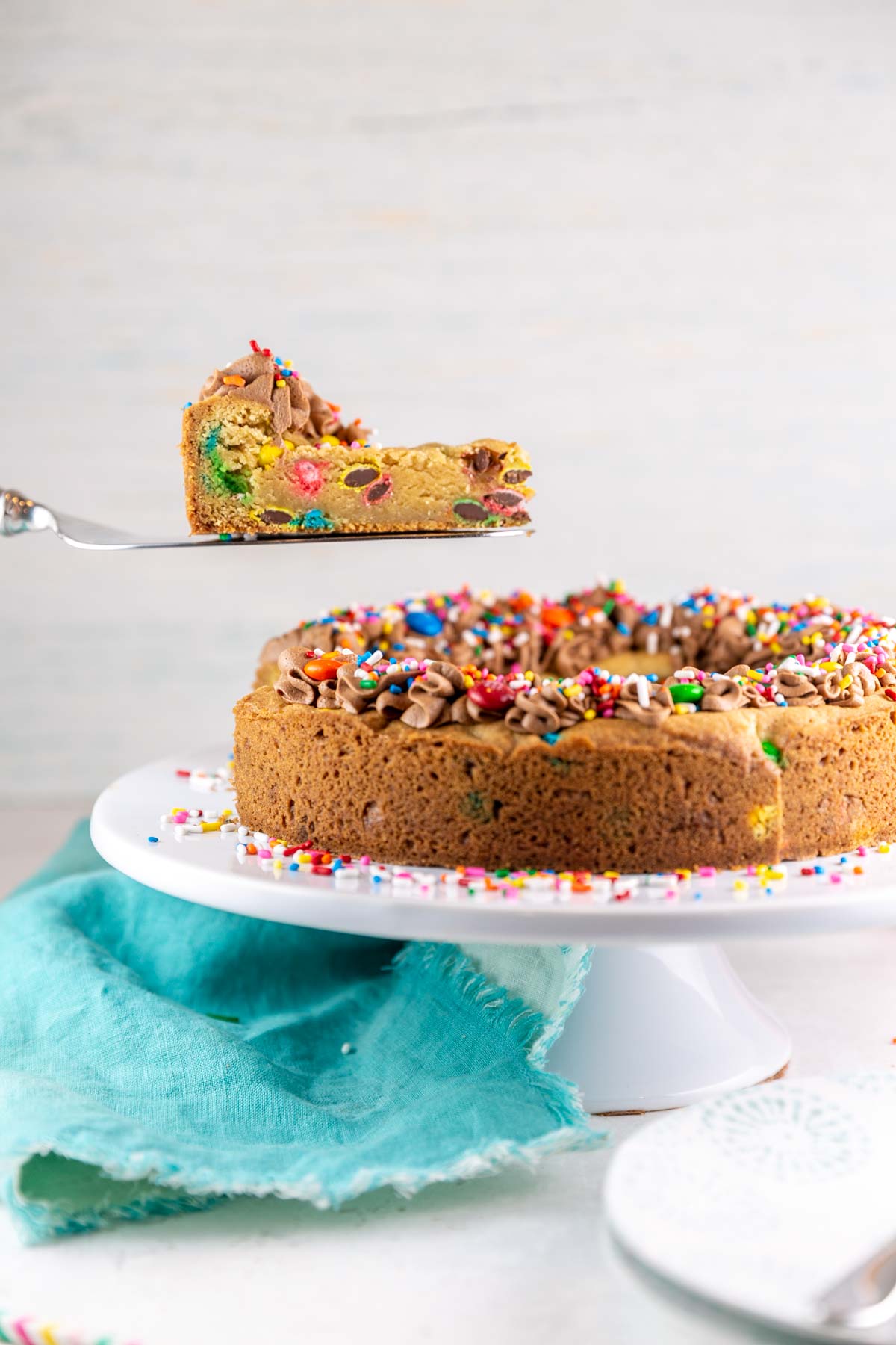 side view of one slice of cookie cake being lifted out from the rest of the cake