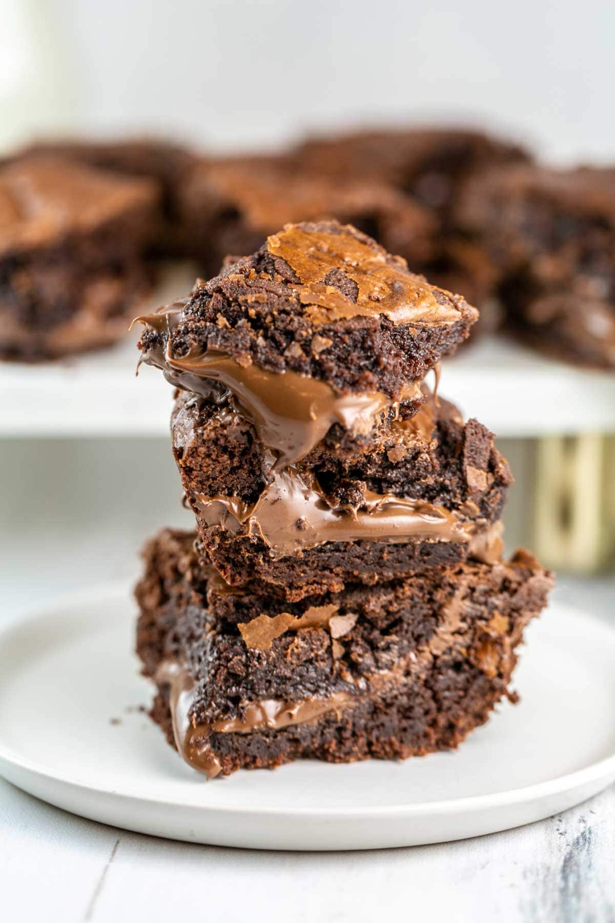 a stack of brownies stuffed with gooey nutella that is oozing out from the middle of the brownies