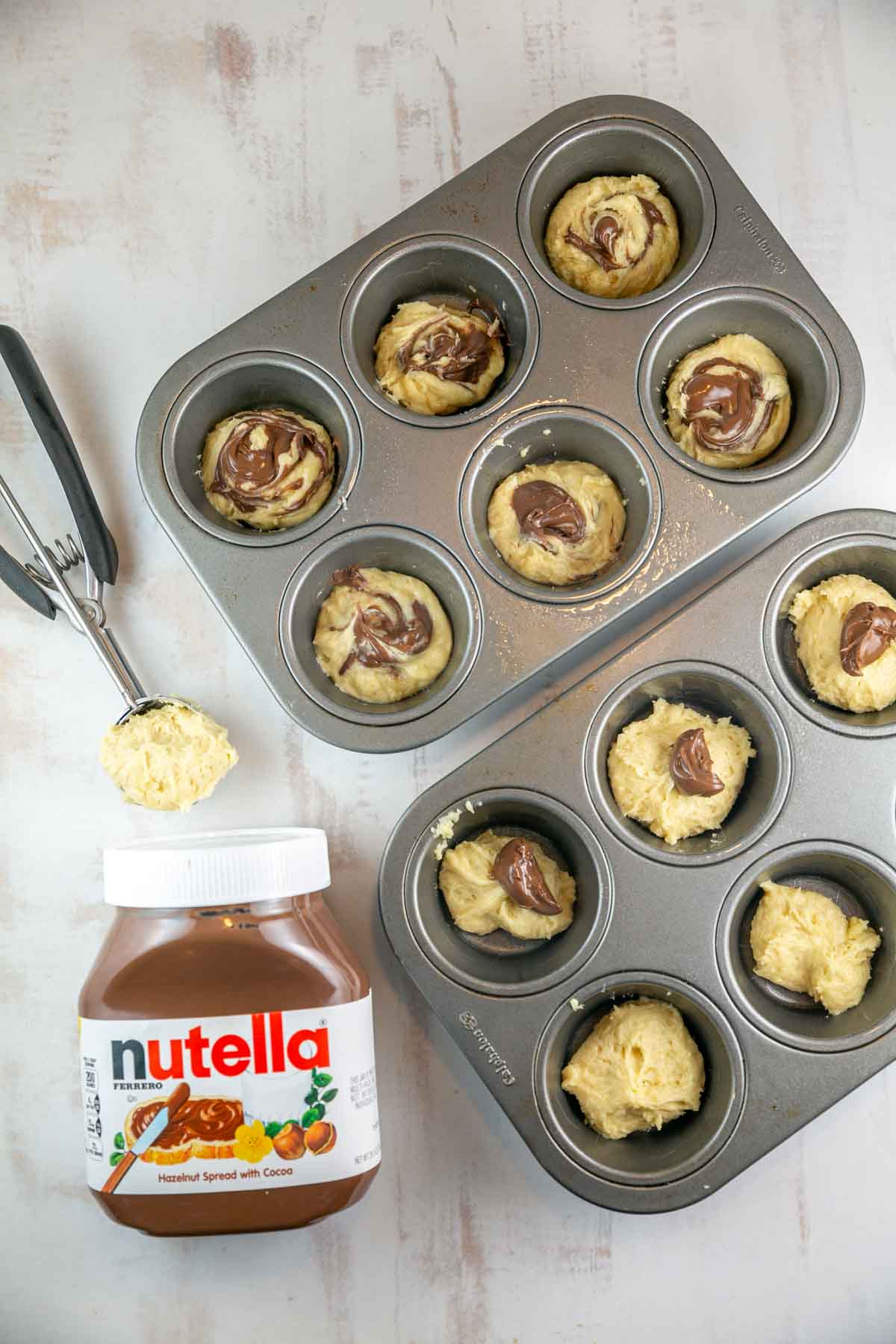 cupcake batter in a muffin tin next to a jar of nutella