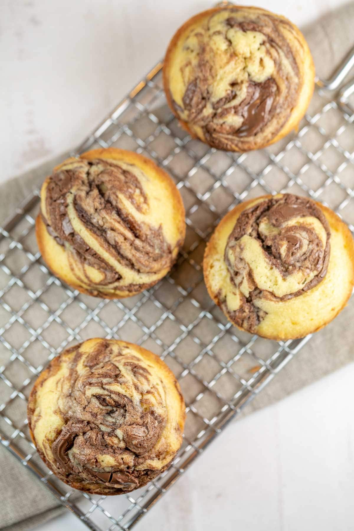 four cupcakes on a wire rack with thick swirls of nutella