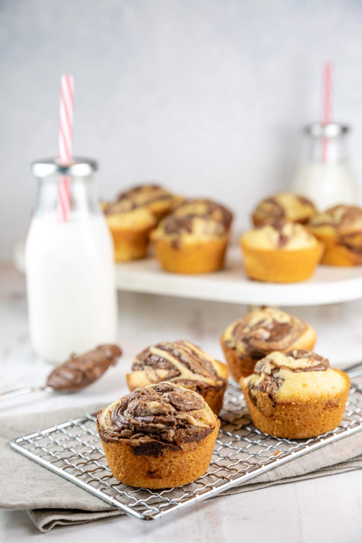 cupcakes on a cooling rack and a marble stand with glass milk bottles in the background