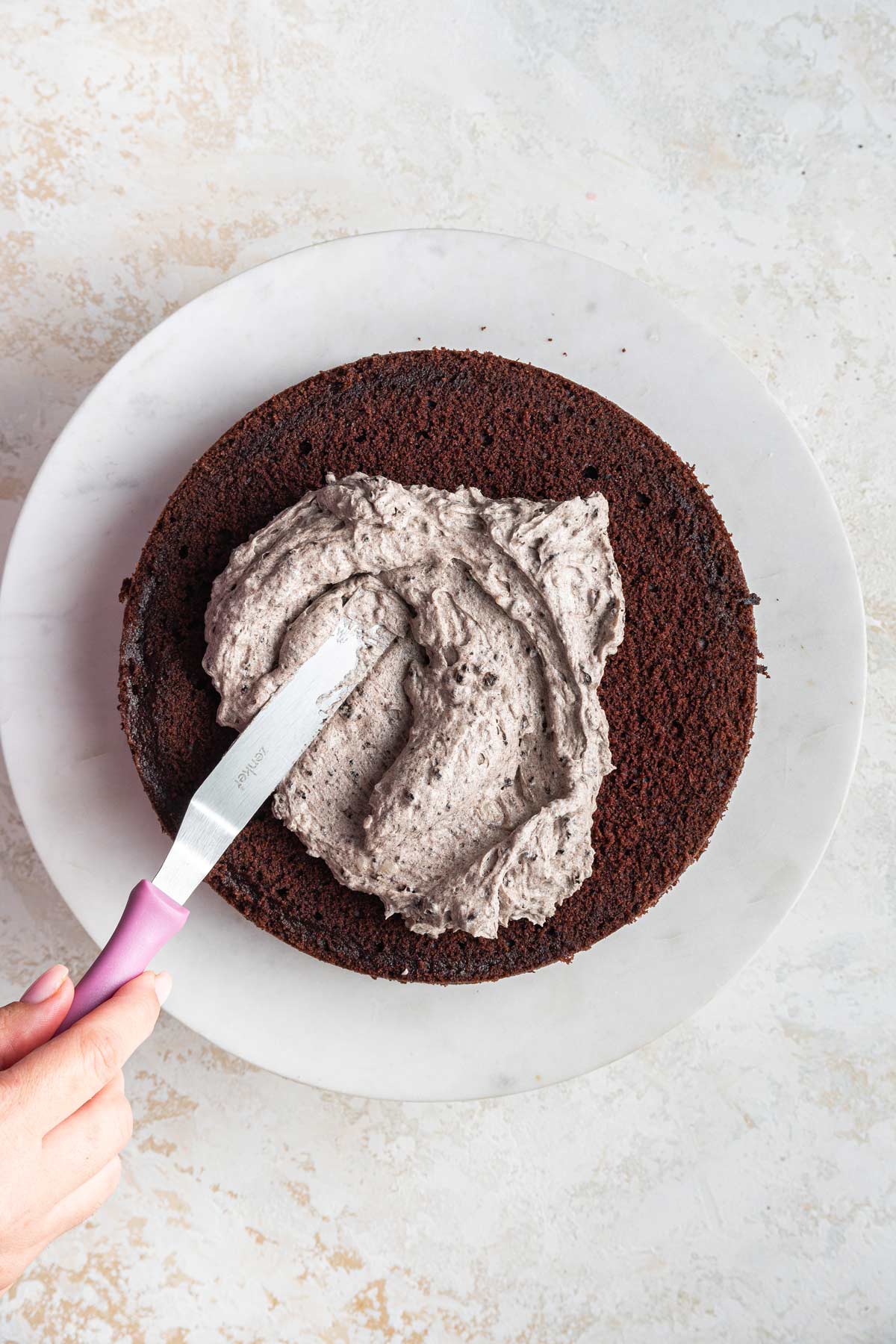 spreading frosting on a cake with a spatula