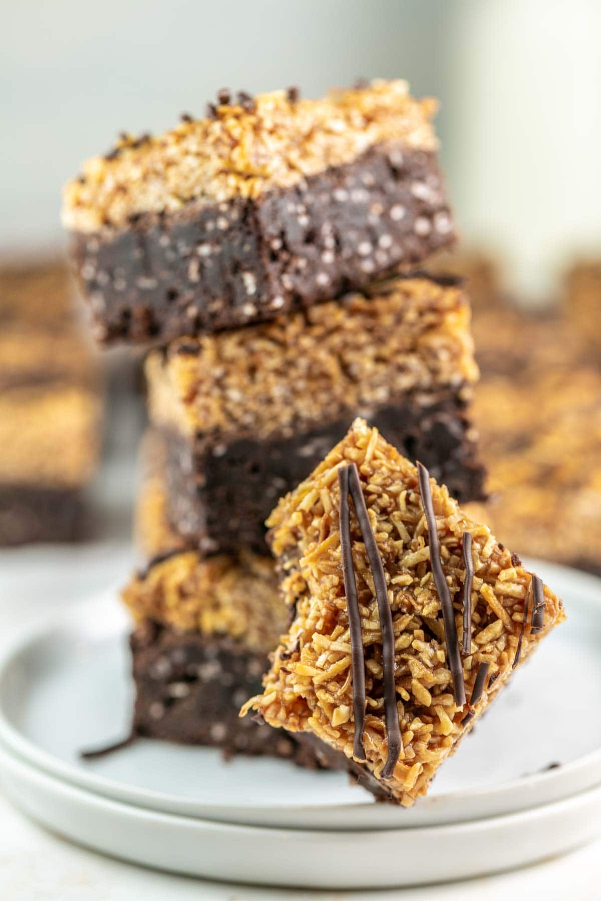 three samoa brownies stacked on a plate with a bitten brownie on the side