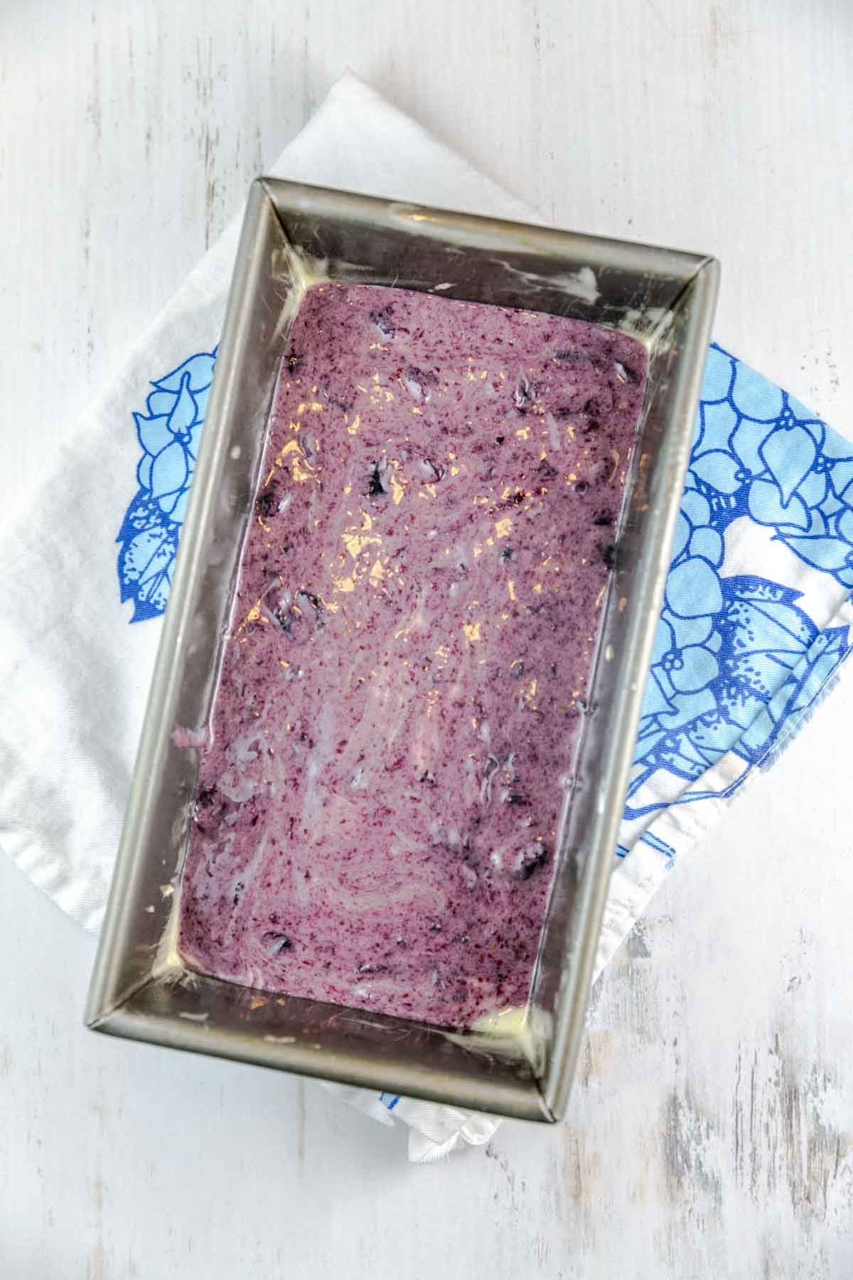 Batter in a loaf pan with blueberry sauce layered on top. 