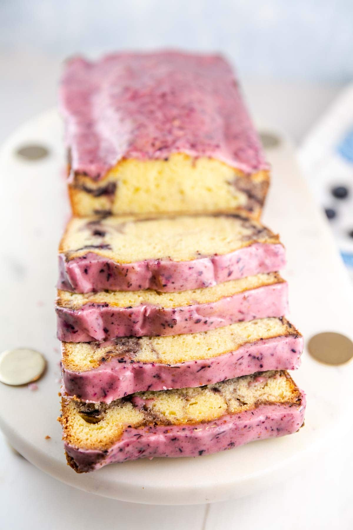 Lemon pound cake loaf with some slices stacked on each other on a white platter.