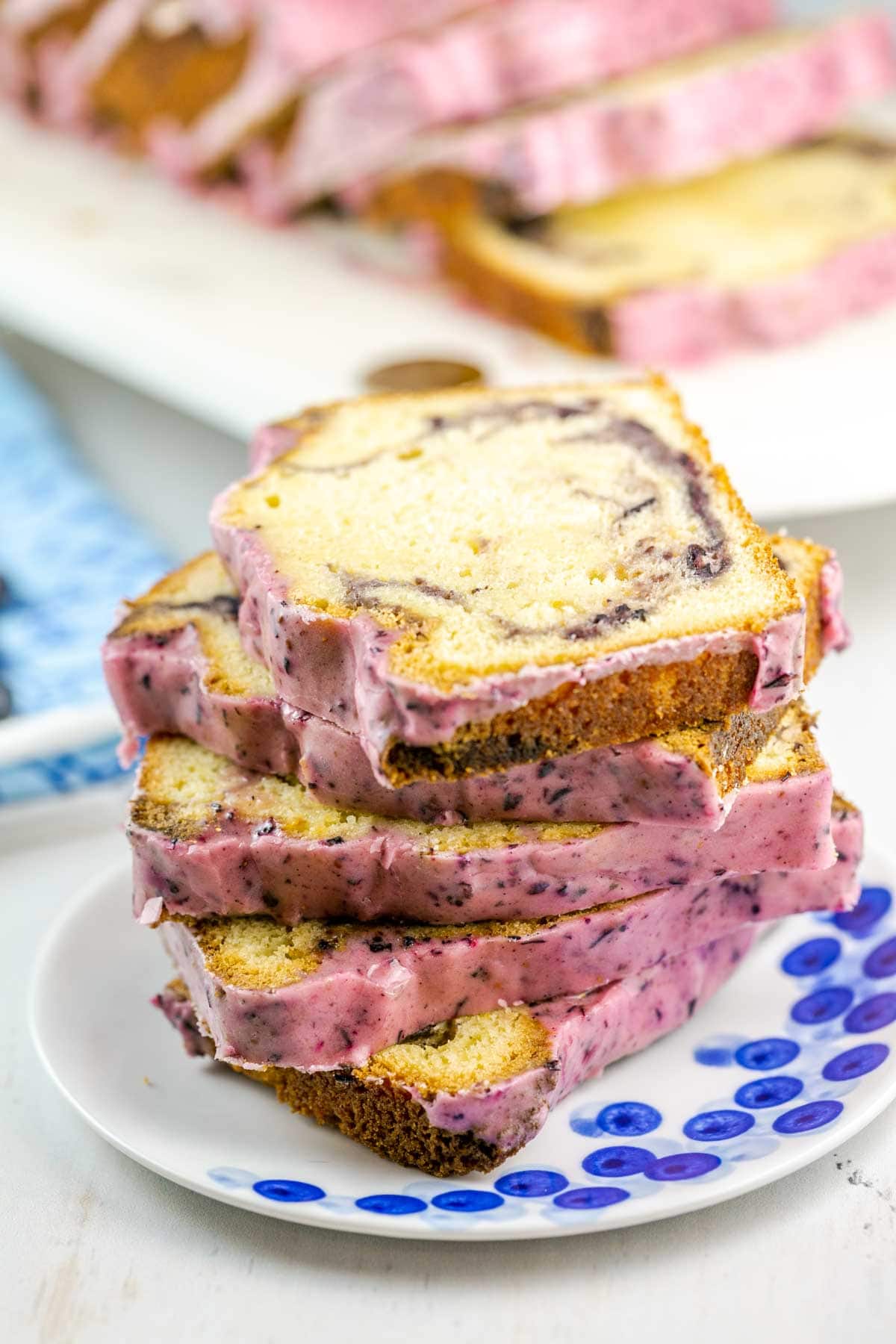 Slices of pound cake stacked on top of each other on a white plate with blue dots. 