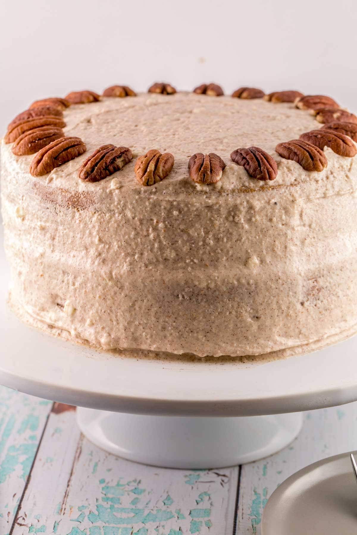 a two layer carrot cake covered in lemon cinnamon cream cheese frosting and pecans