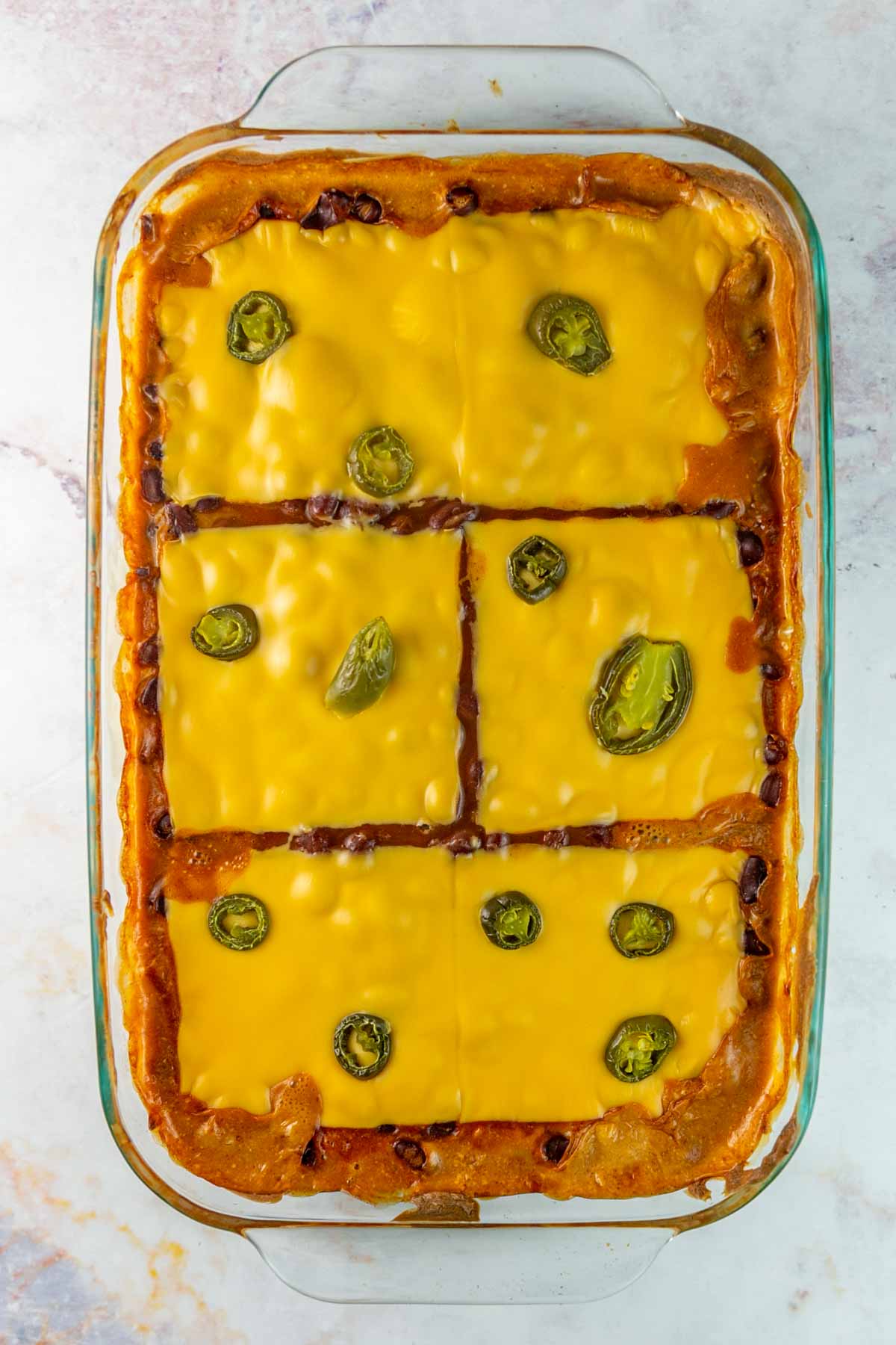 glass serving dish filled with bean dip and covered with melted cheese