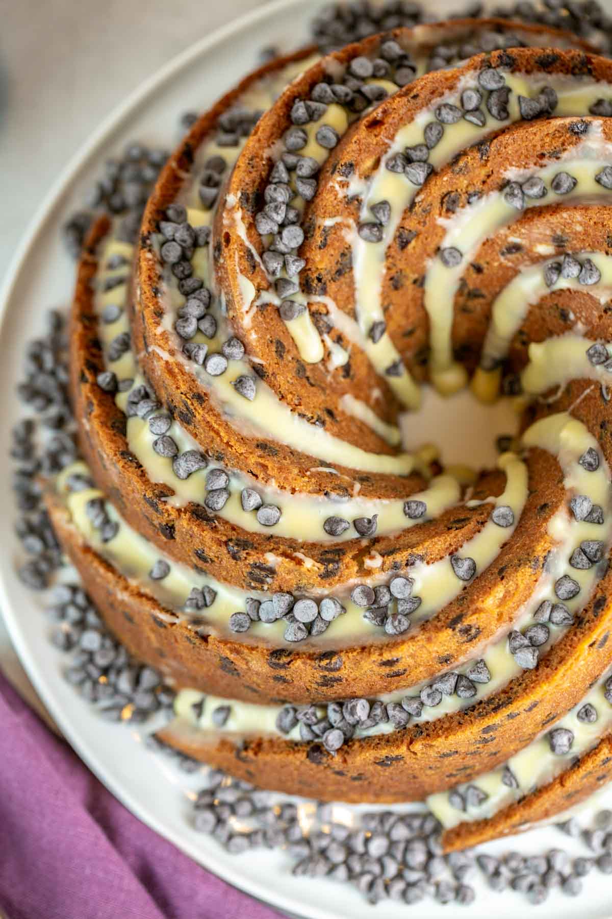 Top view of whole chocolate chip bundt cake with white chocolate glaze and chocolate chips on top.