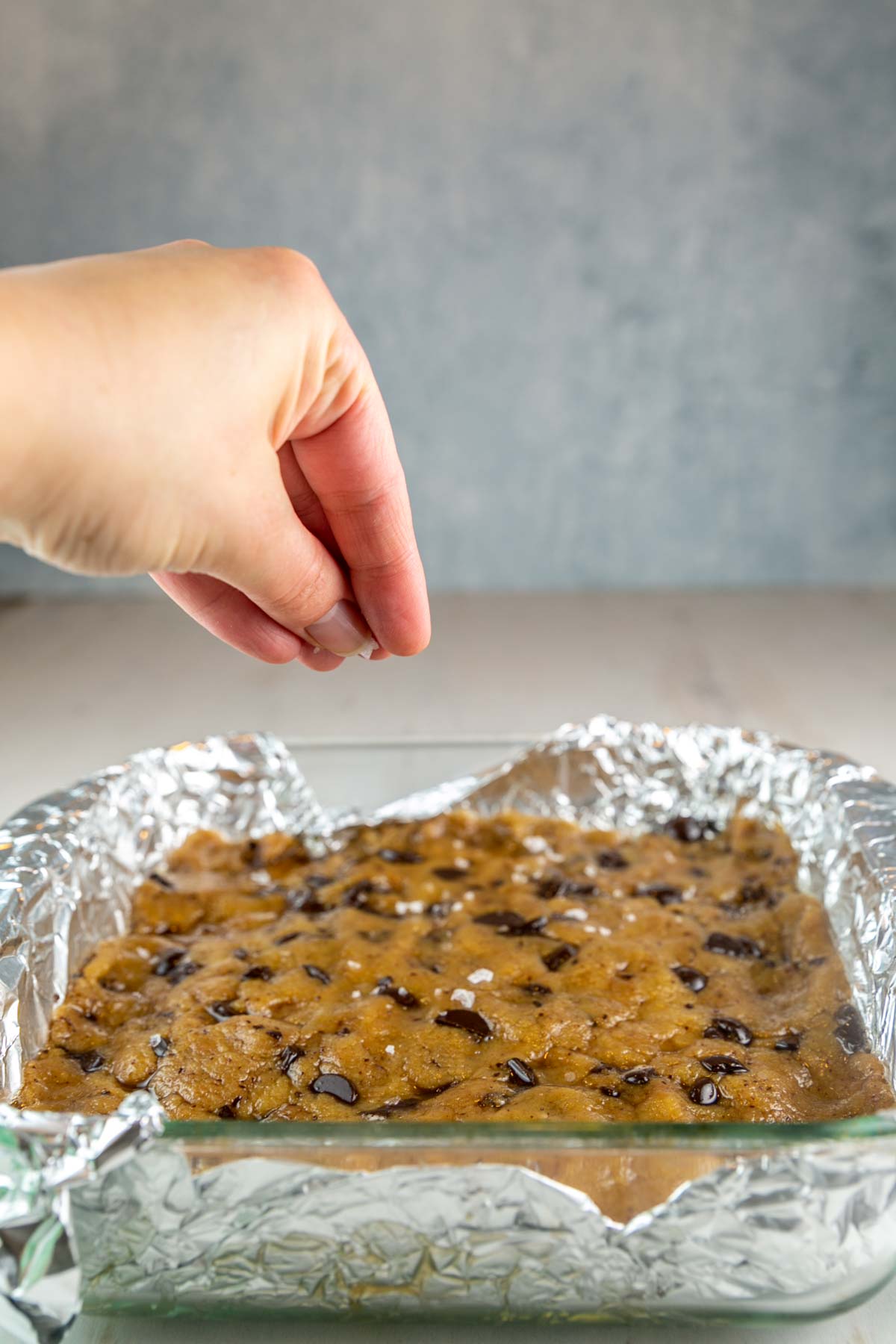 picture of a hand sprinkling salt on top of blondie batter