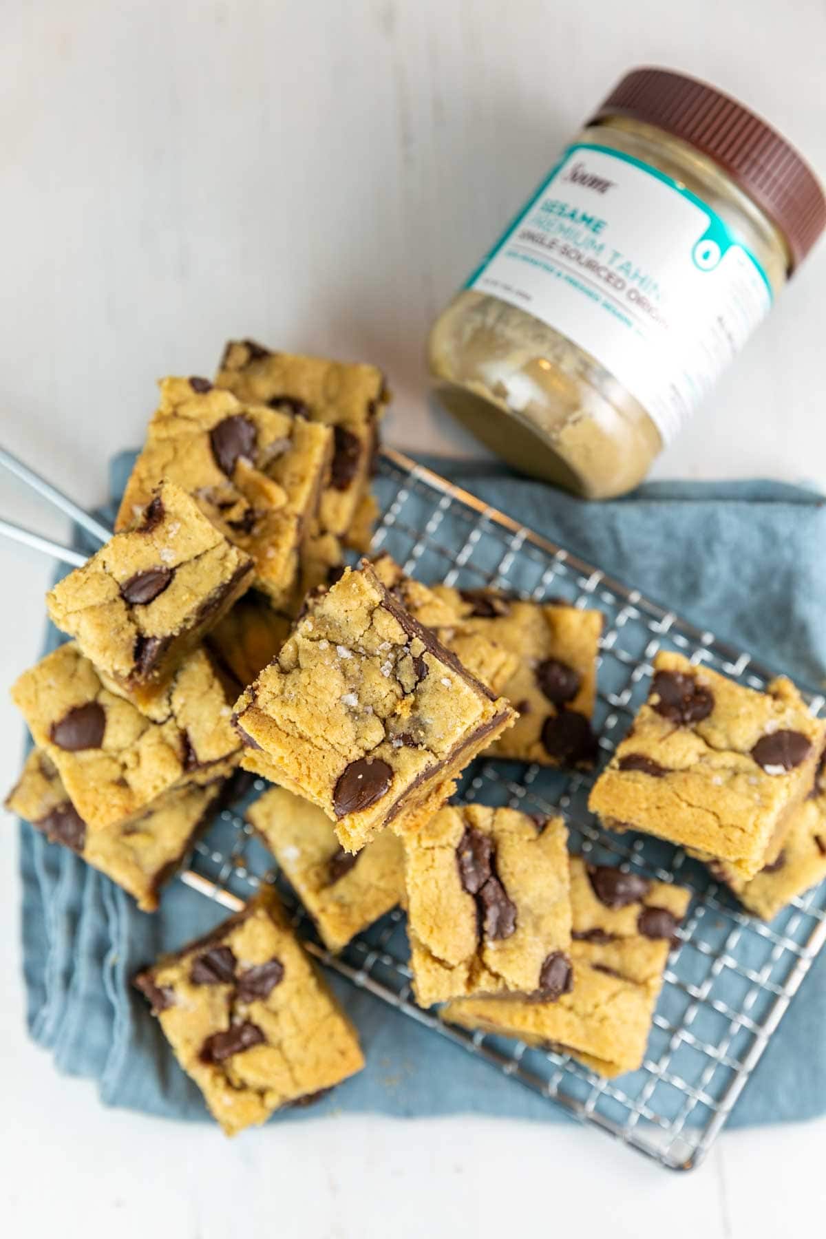 a pile of salted chocolate chip tahini blondies next to a jar of soom tahini