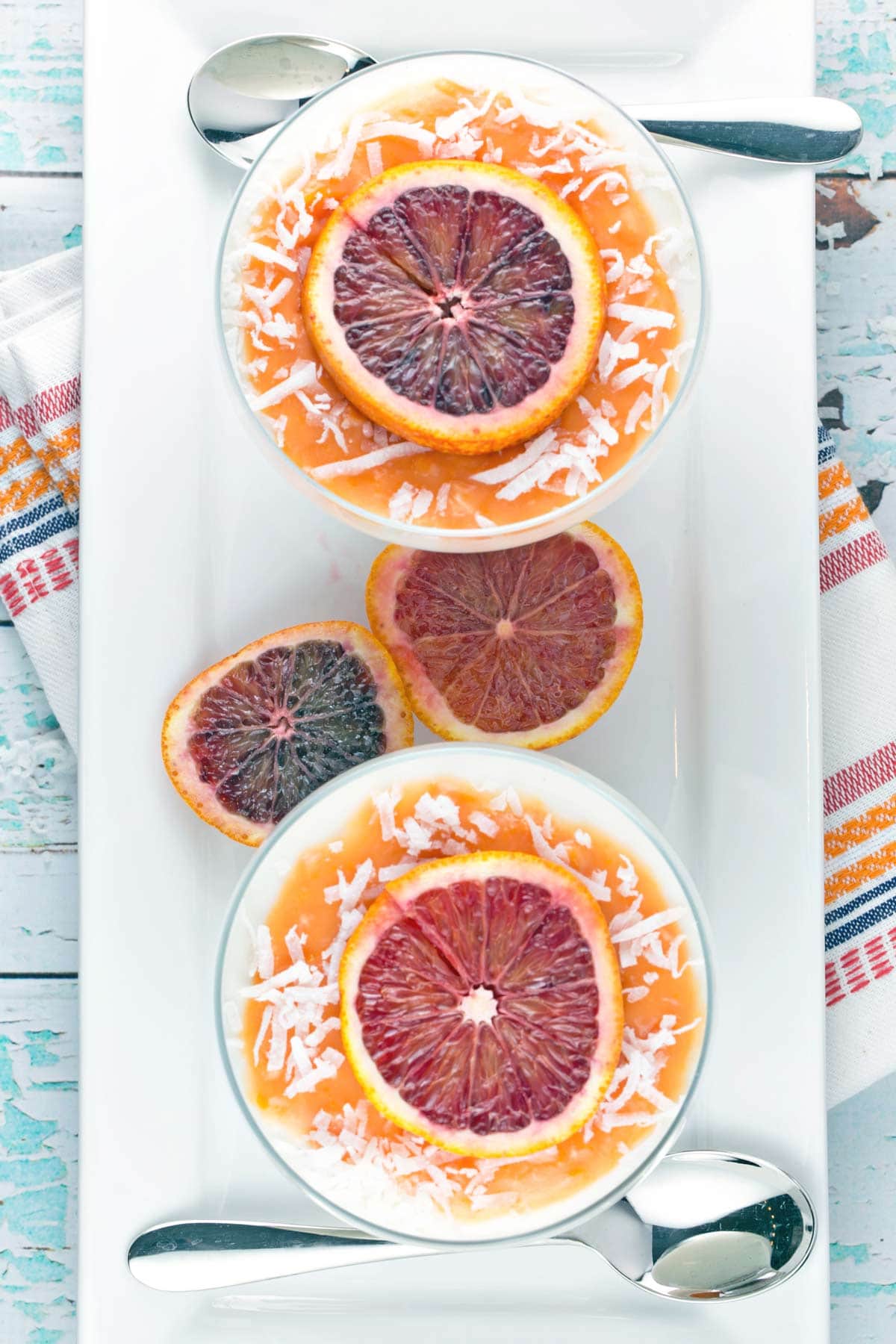 overhead view of two bowls of panna cotta topped with orange slices and shredded coconut