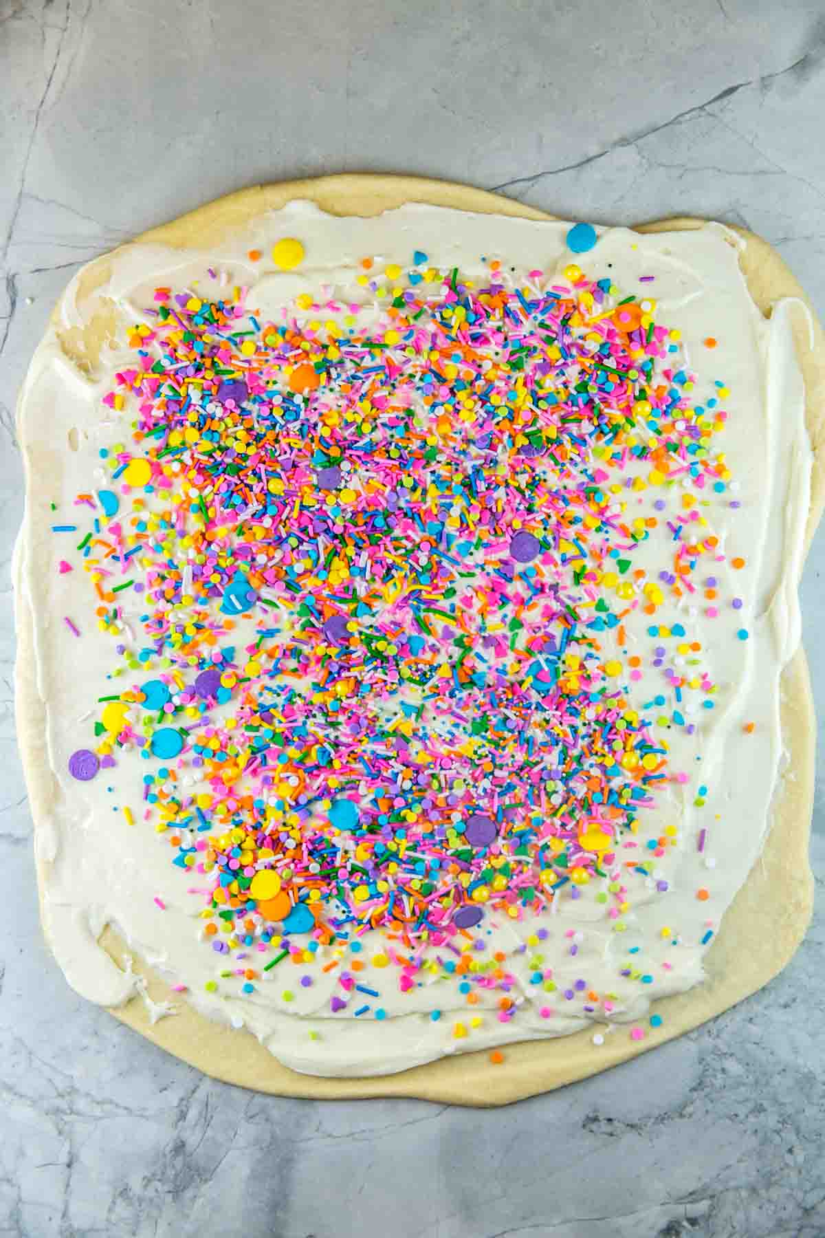 babka bread dough rolled out into a rectangle and covered with cream cheese filling and a layer of sprinkles