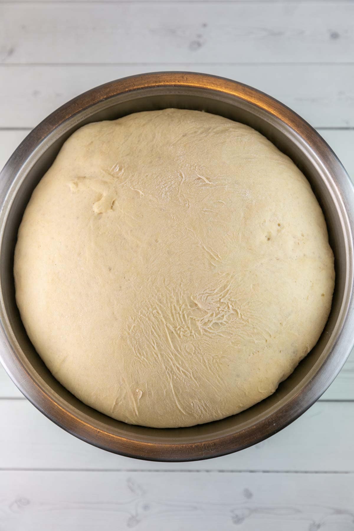 proofed pizza dough in a large metal bowl