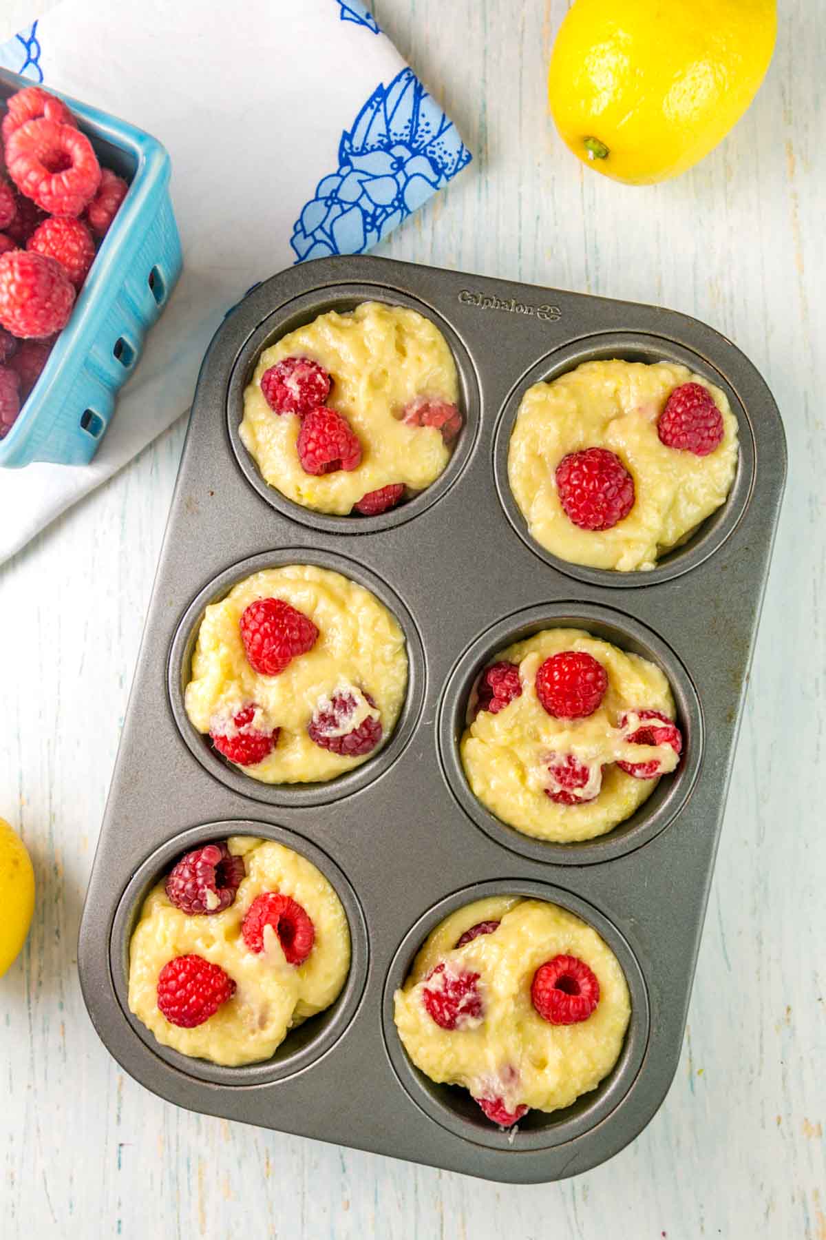 layering muffin batter and raspberries in a muffin tin