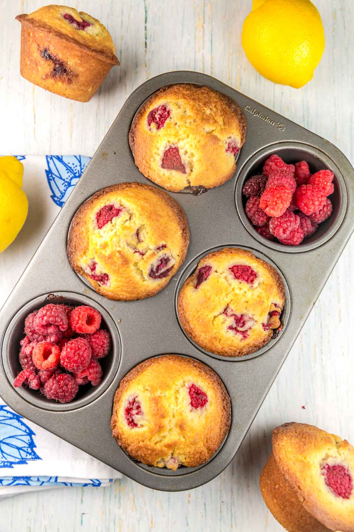 four muffins in a 6 well tin with raspberries in two of the wells