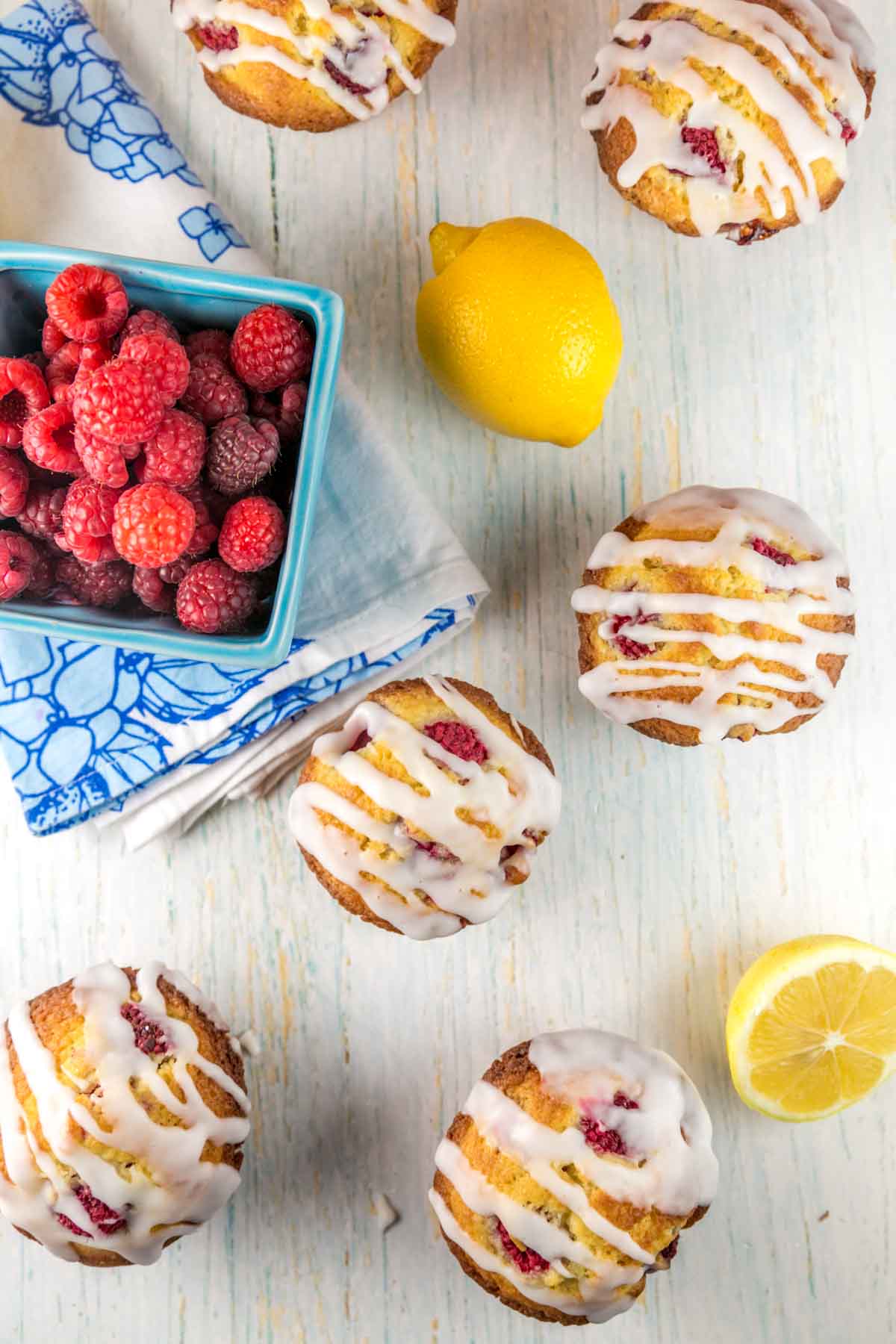 raspberry muffins with drizzles of lemon glaze next to a berry basket full of fresh raspberries