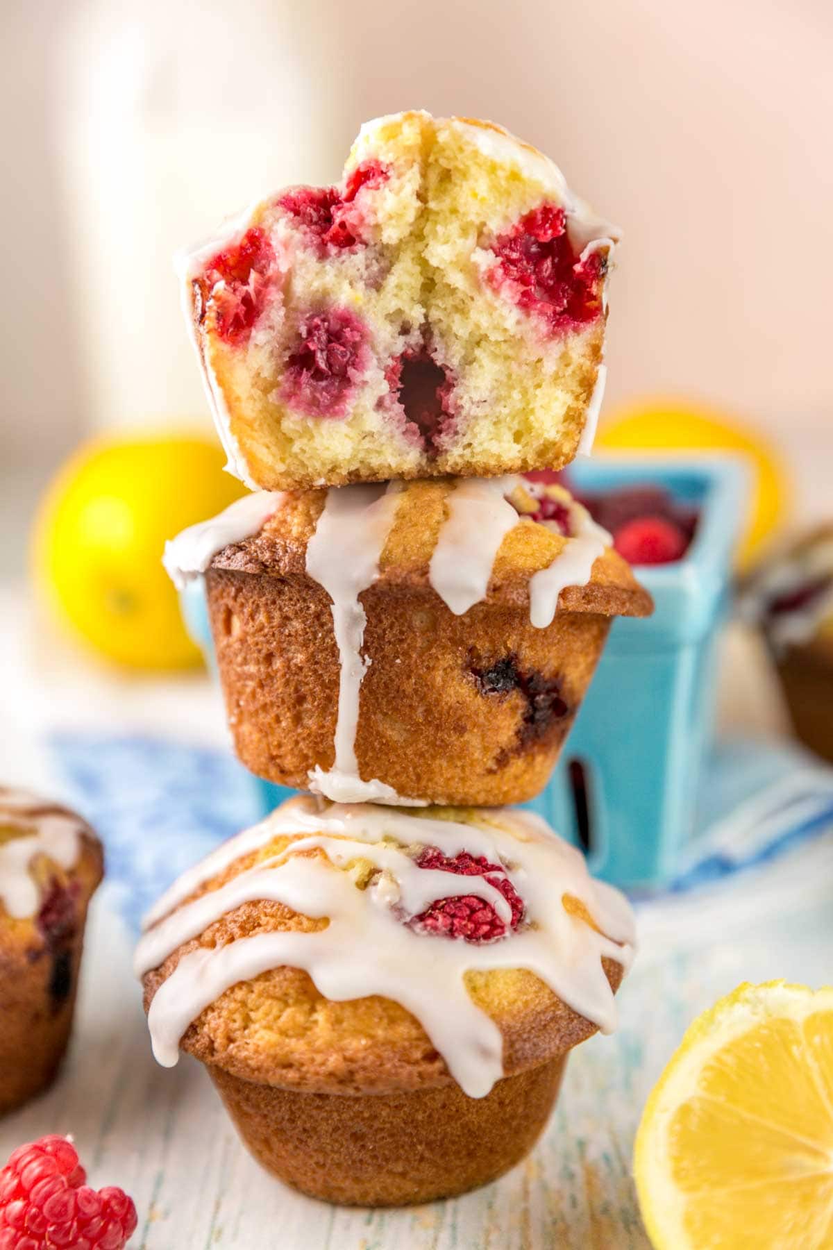 vertical stack of muffins with the top muffin cut in half showing the whole raspberries inside