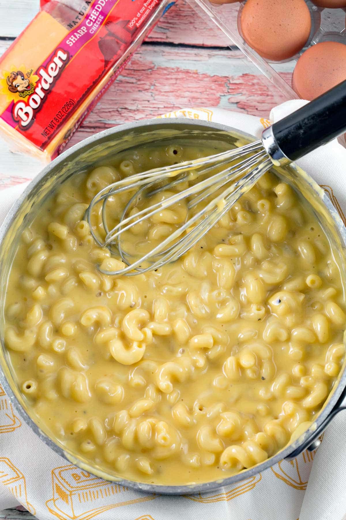 a large saucepan filled with creamy macaroni and cheese with a pale yellow cheesy sauce