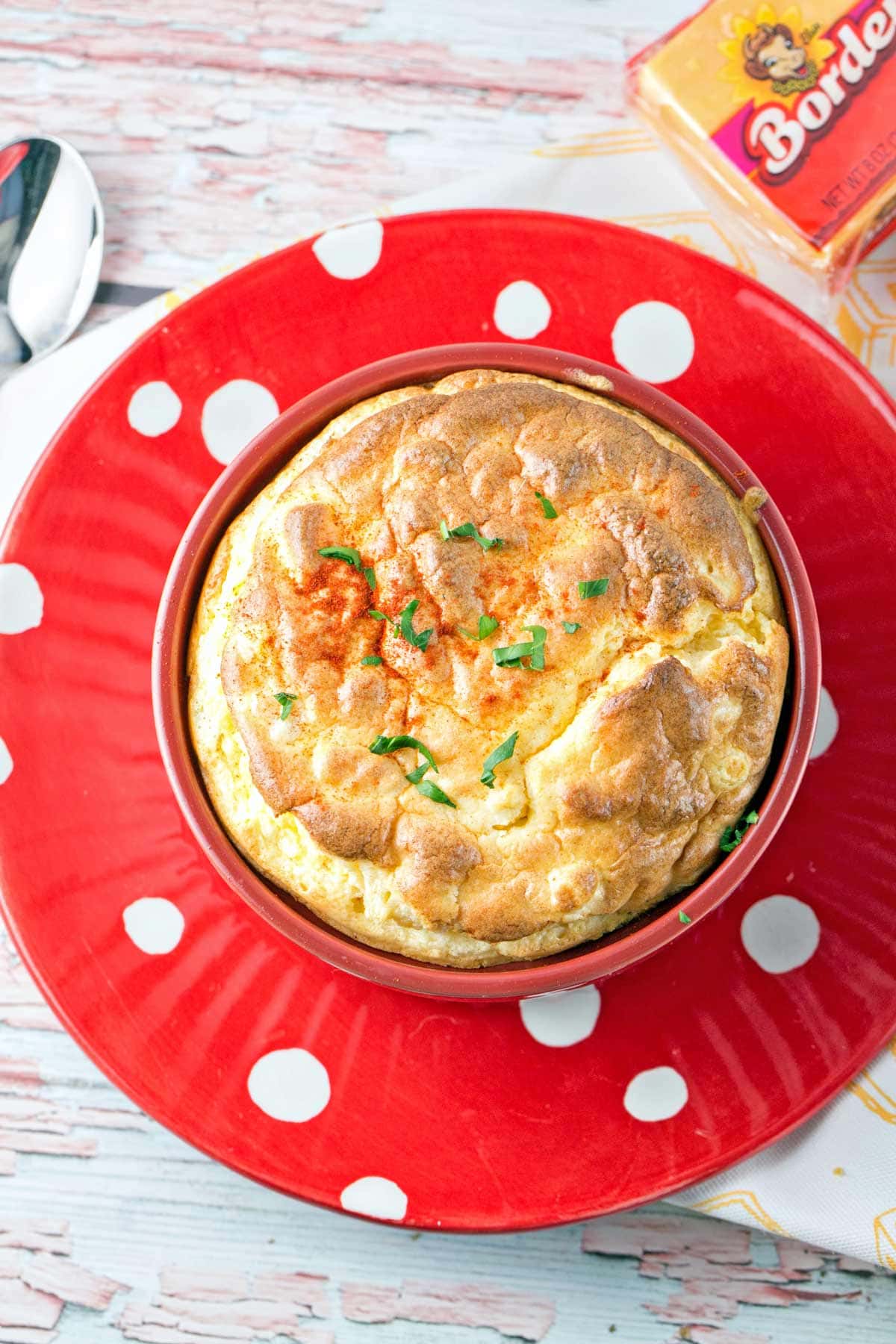 baked macaroni and cheese souffle with a browned cheesy top in a red ramekin