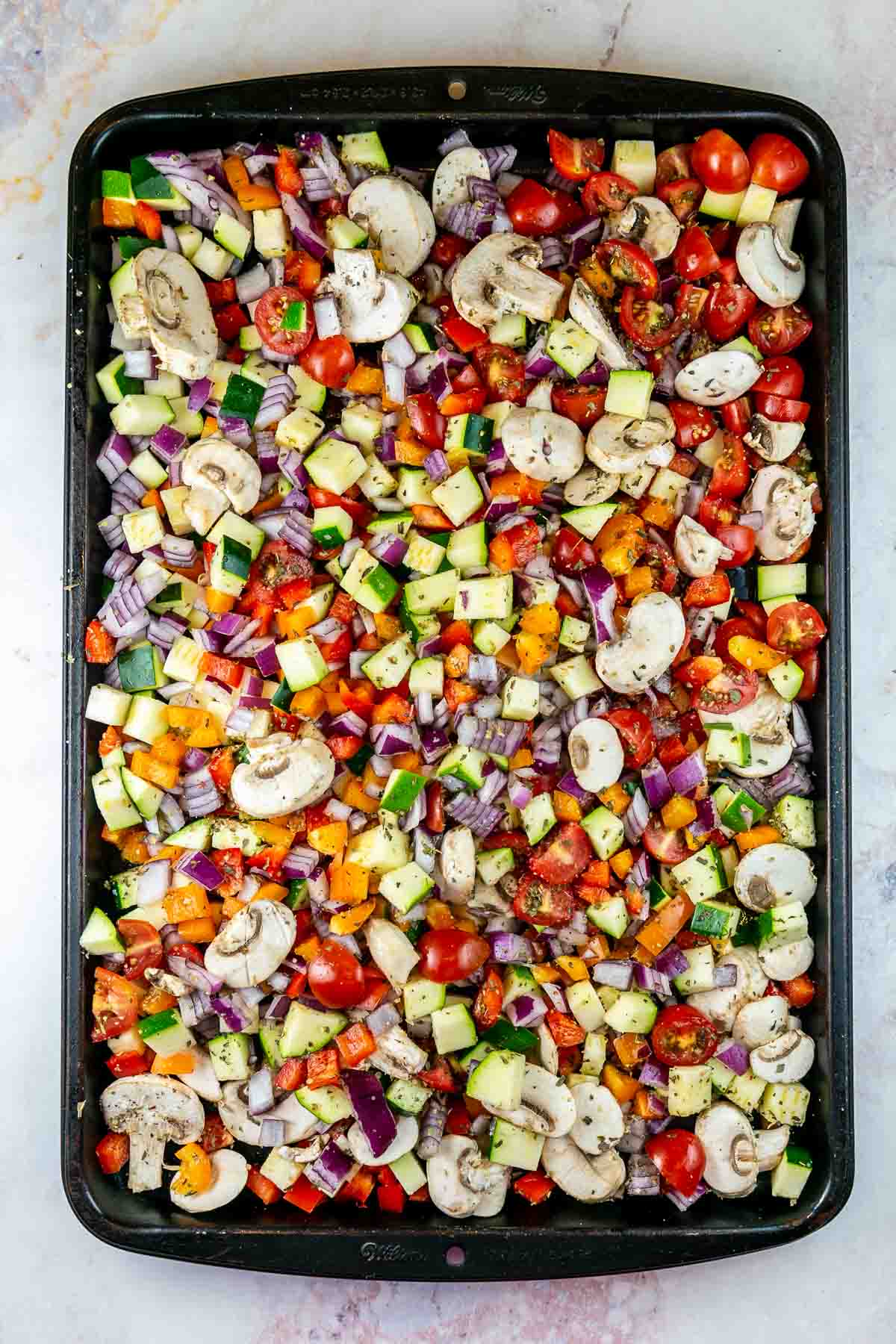 Top view of baking sheet filled with vegetables prior to being roasted. 