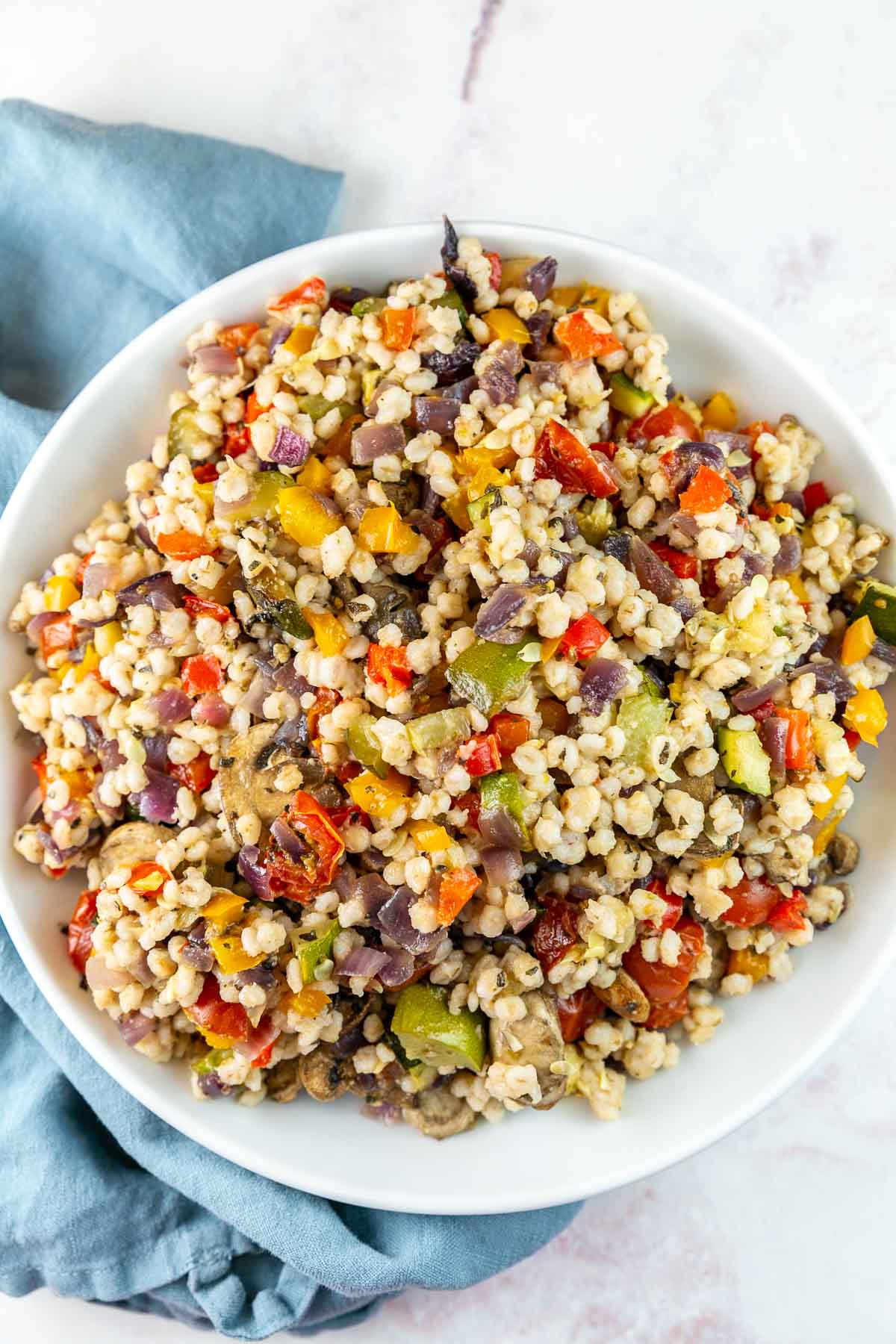 White serving bowl filled with Mediterranean barley salad.