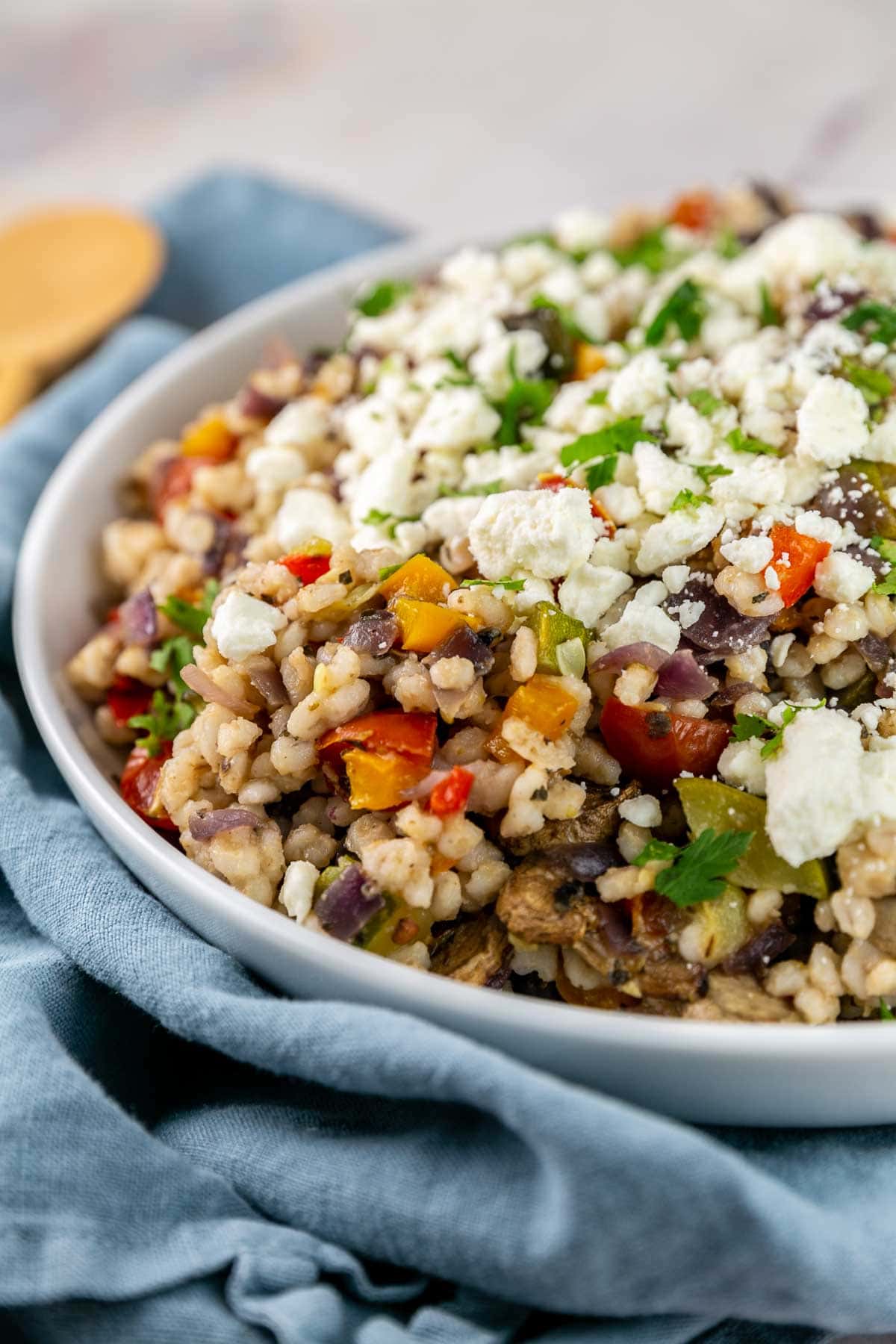 White serving bowl filled with barley and roasted vegetables.