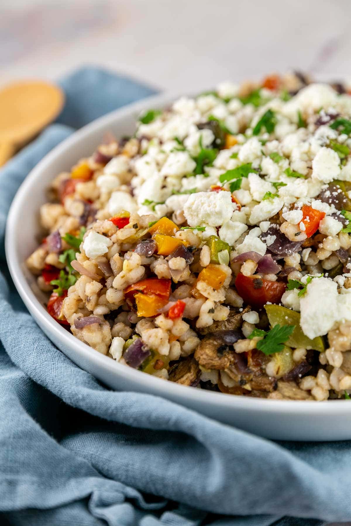 White serving bowl filled with barley and roasted vegetables. 