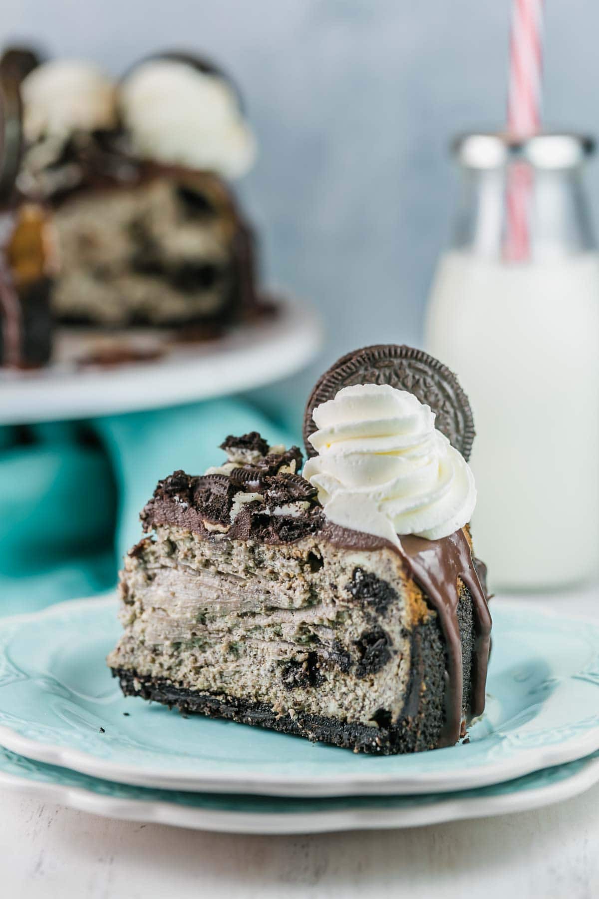a large slice of cheesecake filled with oreos on a stack of dessert plates