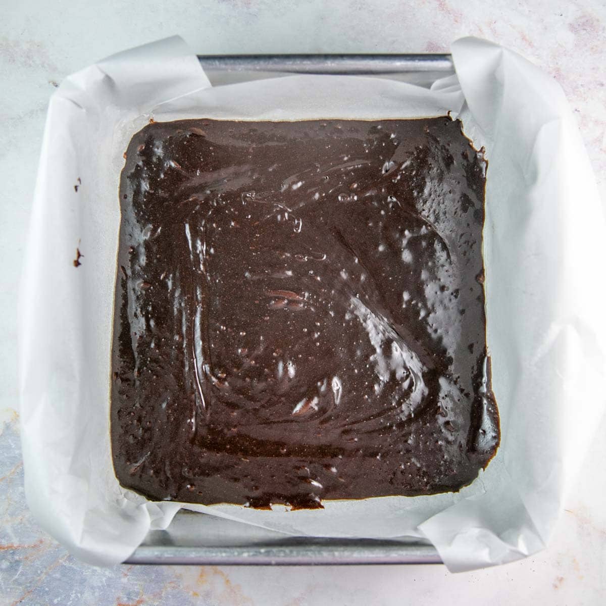 brownie batter in a glass square baking pan