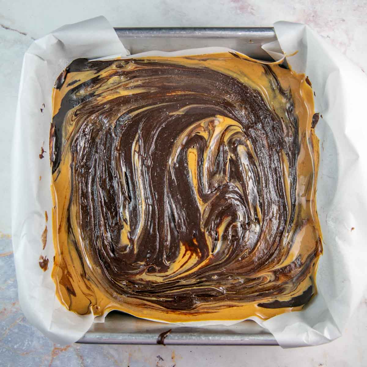 swirling chocolate batter on top of melted peanut butter
