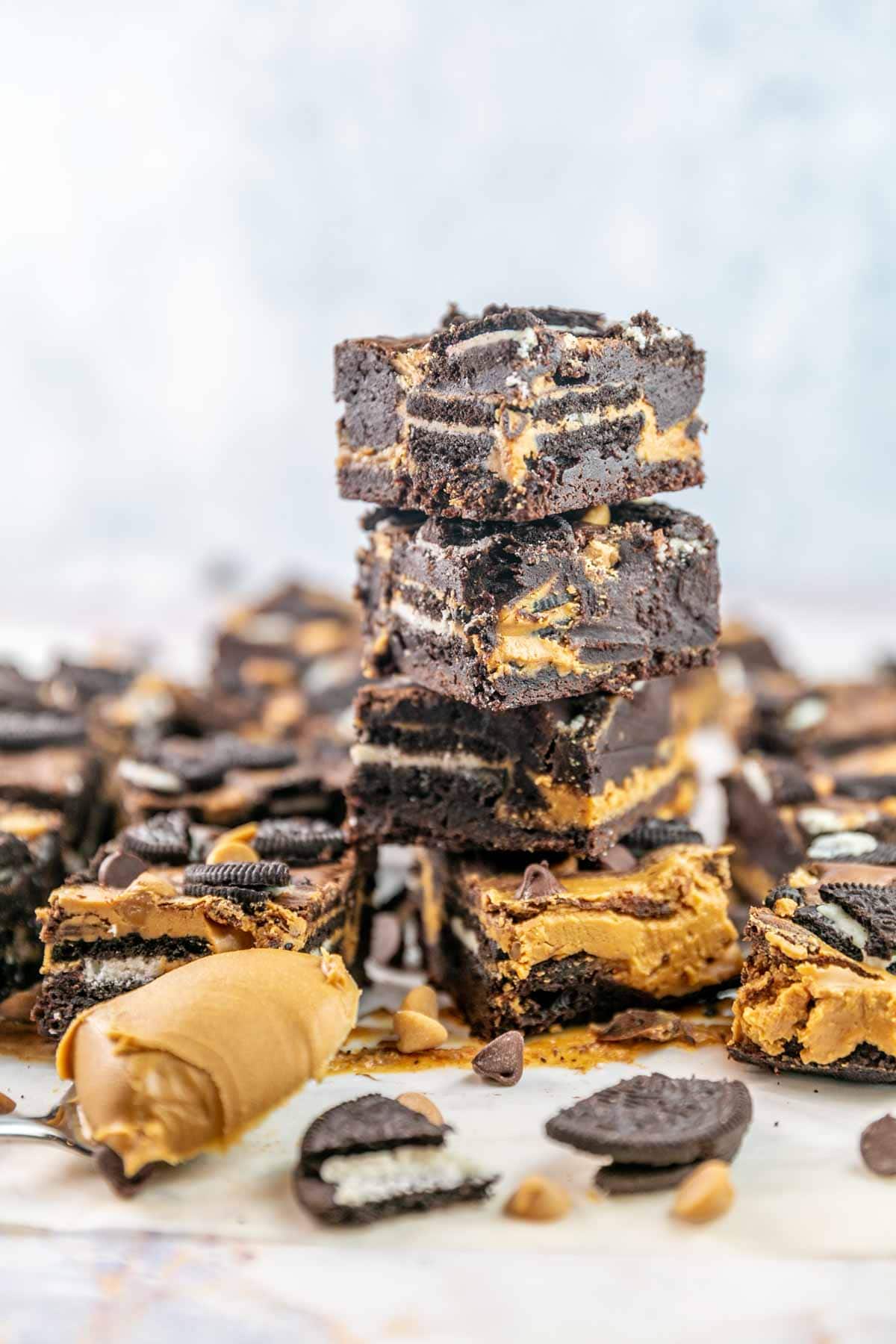 Peanut butter Oreo brownies stacked on top of each other with more brownies in the background. 