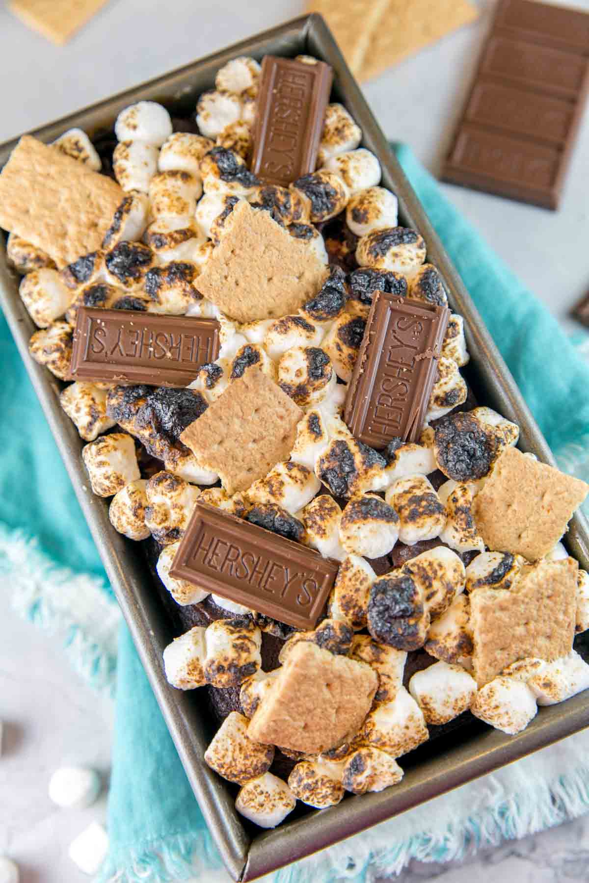 s'mores quick bread in a loaf pan covered with toasted marshmallows, graham crackers, and squares of chocolate