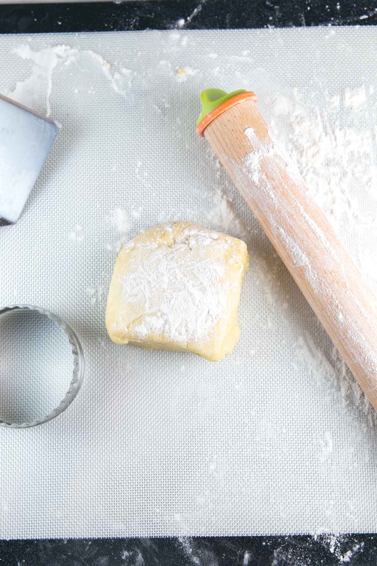 a floured dough mat with a square mound of dough ready to be rolled out