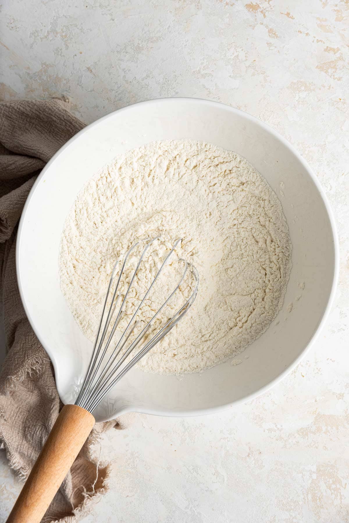 whisk resting in a large mixing bowl full of flour