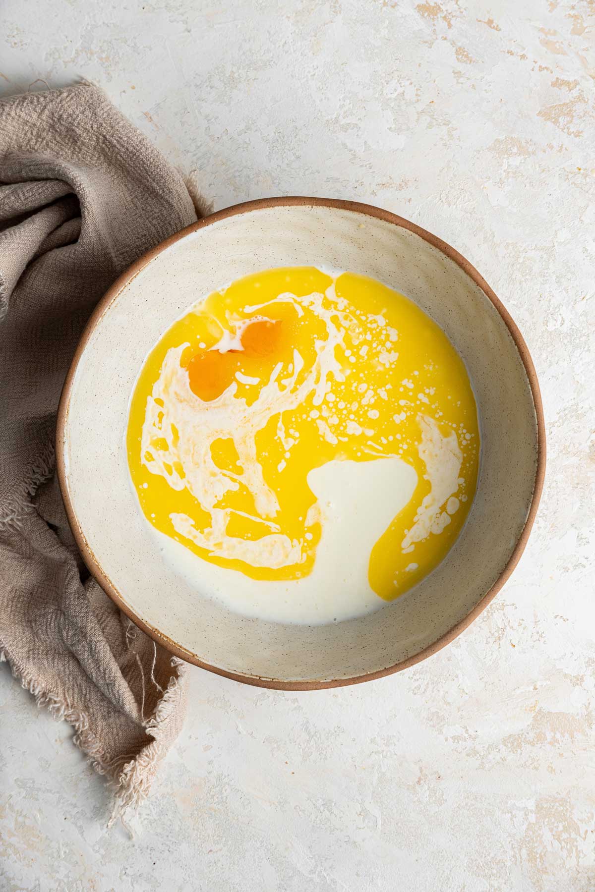 mixing bowl containing melted butter, egg yolks, and milk