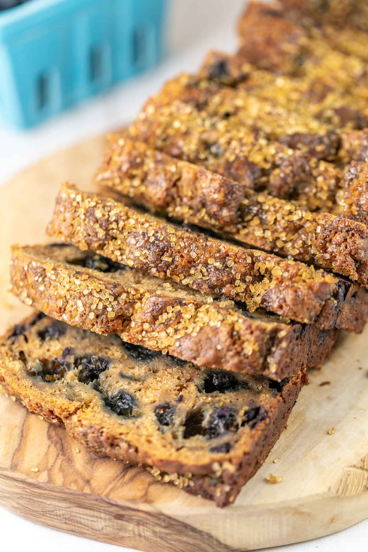 slices of a blueberry honey quick bread on a wooden cutting board