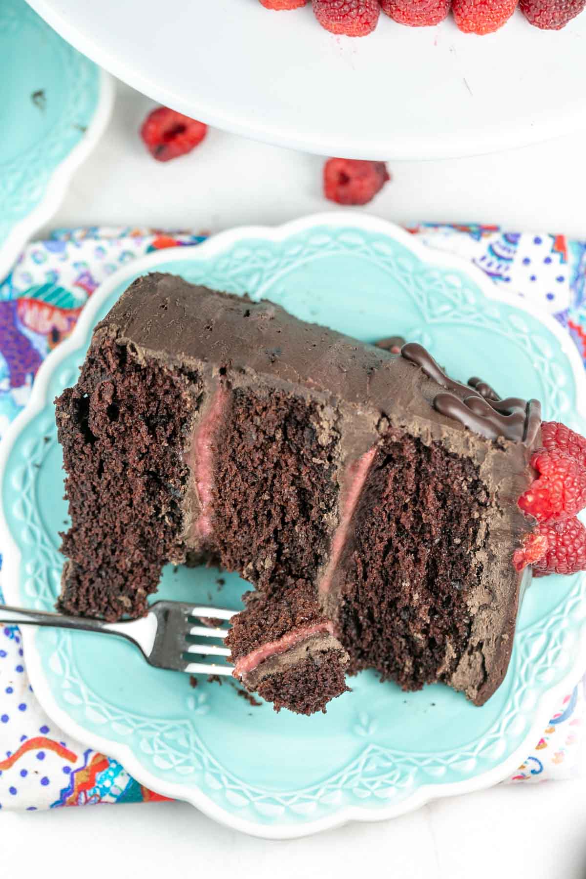 three layer chocolate raspberry cake on a plate with a fork removing one biteful