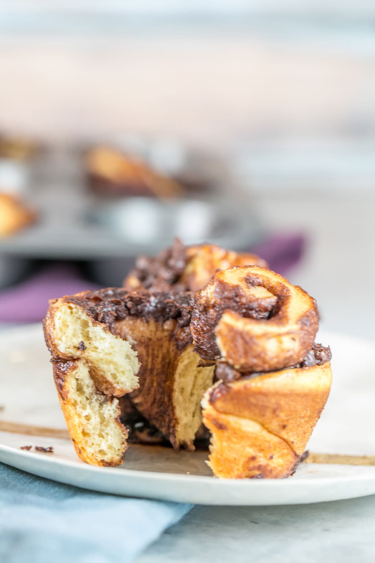 swirled chocolate babka muffin on a plate torn open to show the chocolate swirled inside